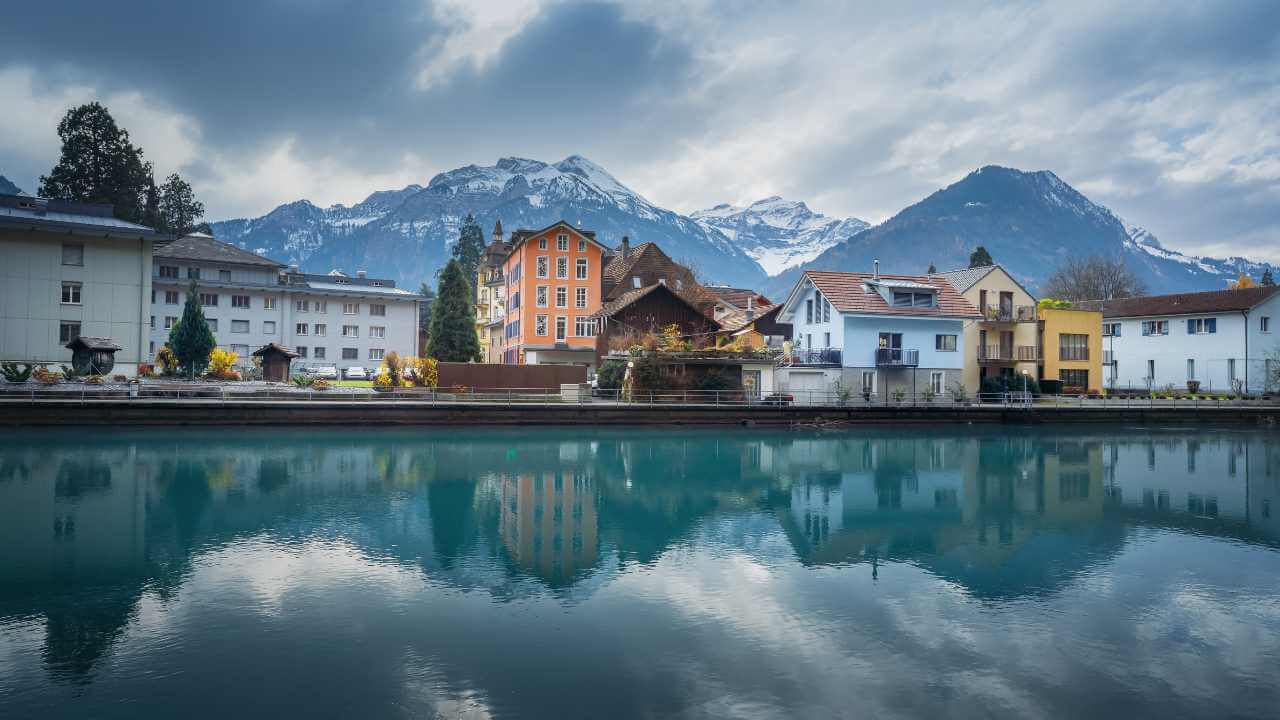 a view of buildings along a river with mountains in the background