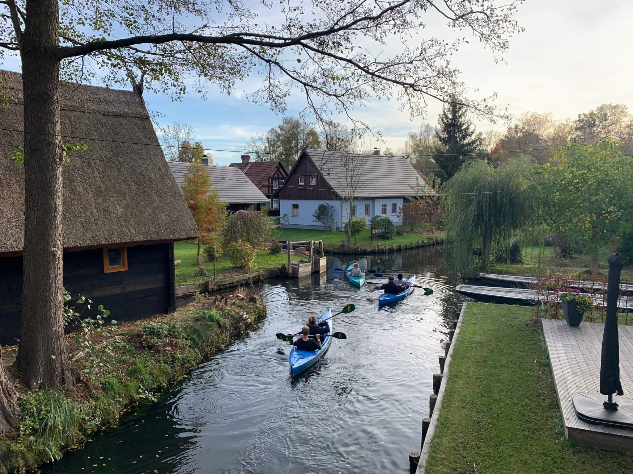 Blue kayaks in a dark stream and lush greenery.