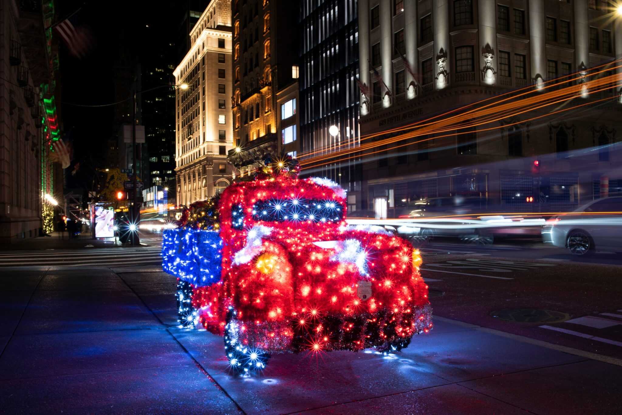 Festive truck covered in holiday lights in Midtown Manhattan at night during winter in New York City.