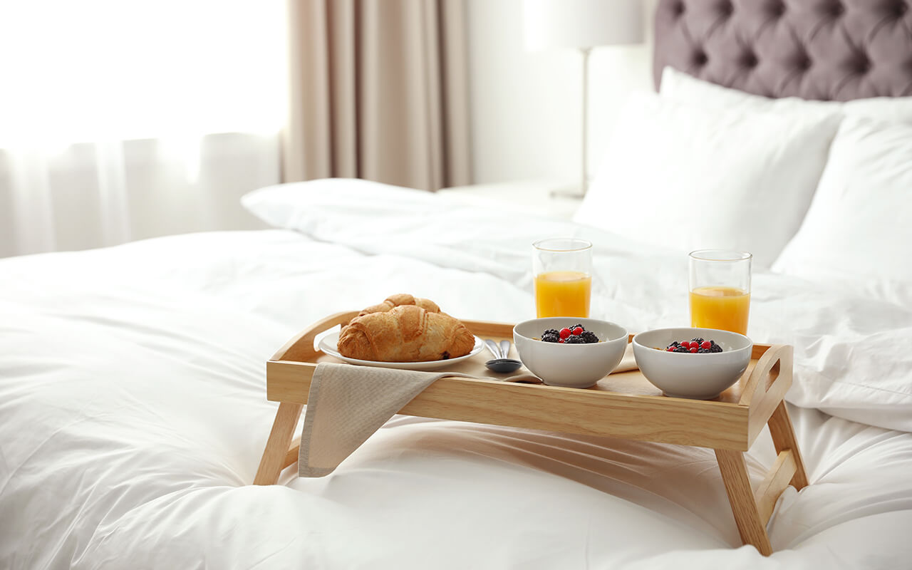 Breakfast on a tray on a hotel bed