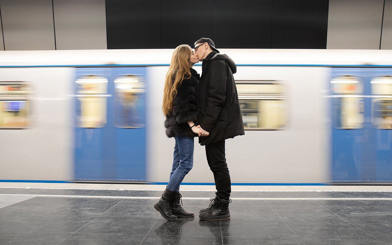 Young couple kiss in the subway underground of Moscow on the background of a moving train