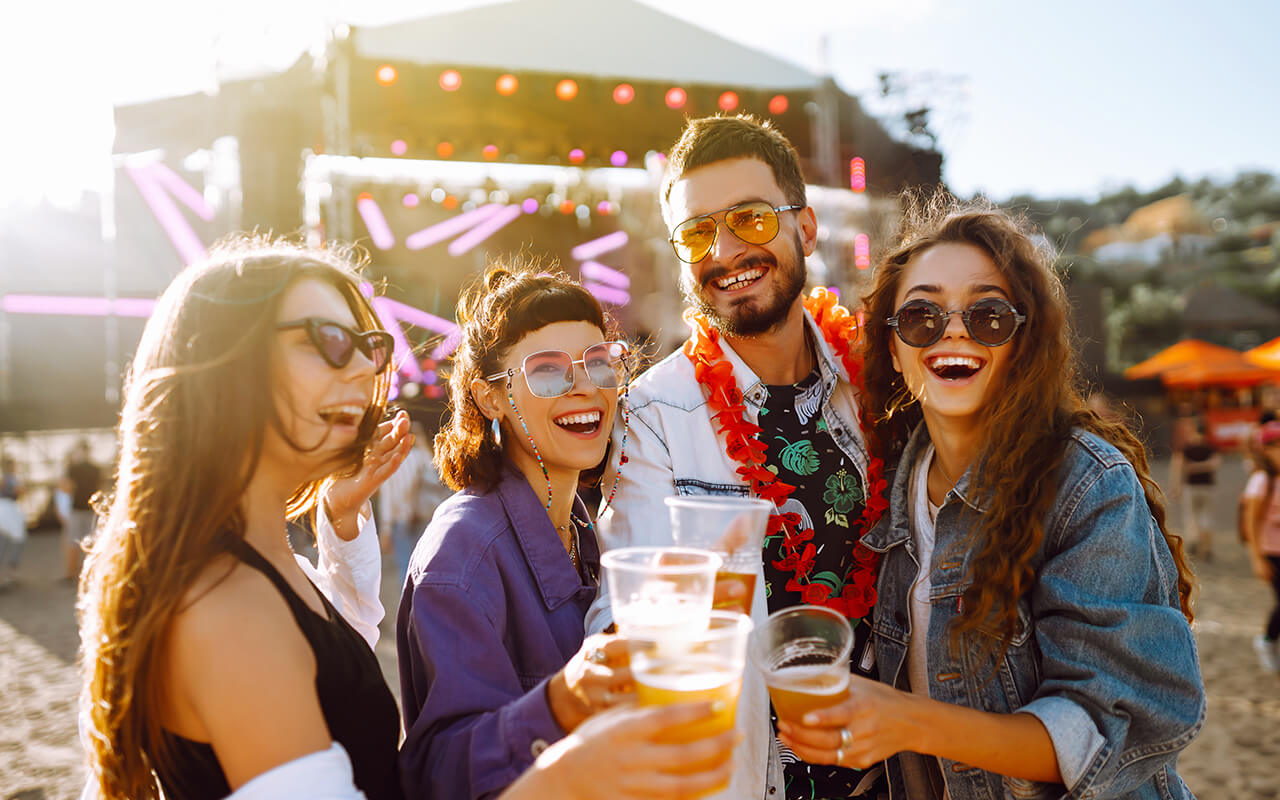 Young happy friends drinking beer and having fun at music festival together.
