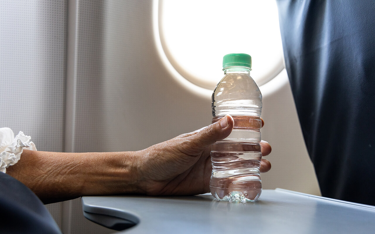 Person holding a water bottle on an airplane