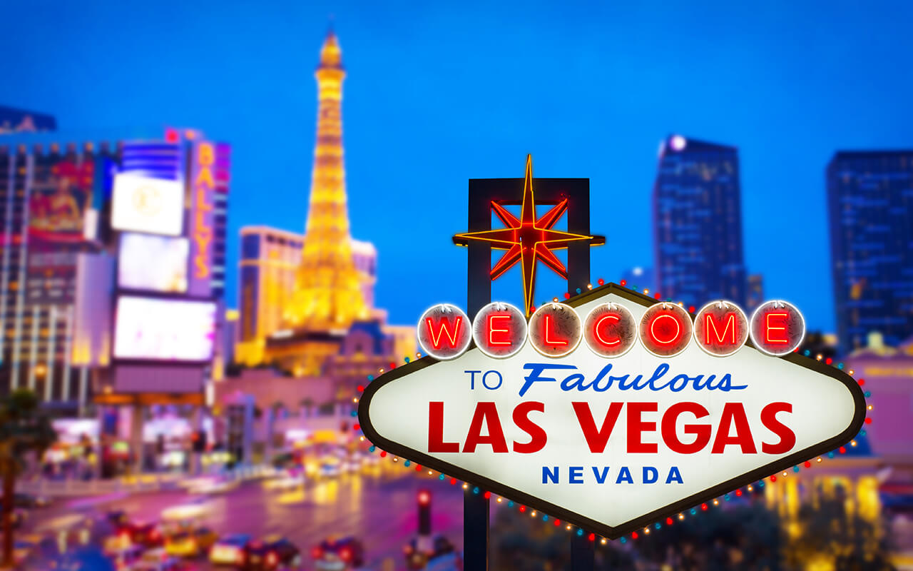 Welcome to Fabulous Las Vegas Nevada neon sign illuminated at night with blurred casino skyline in the background
