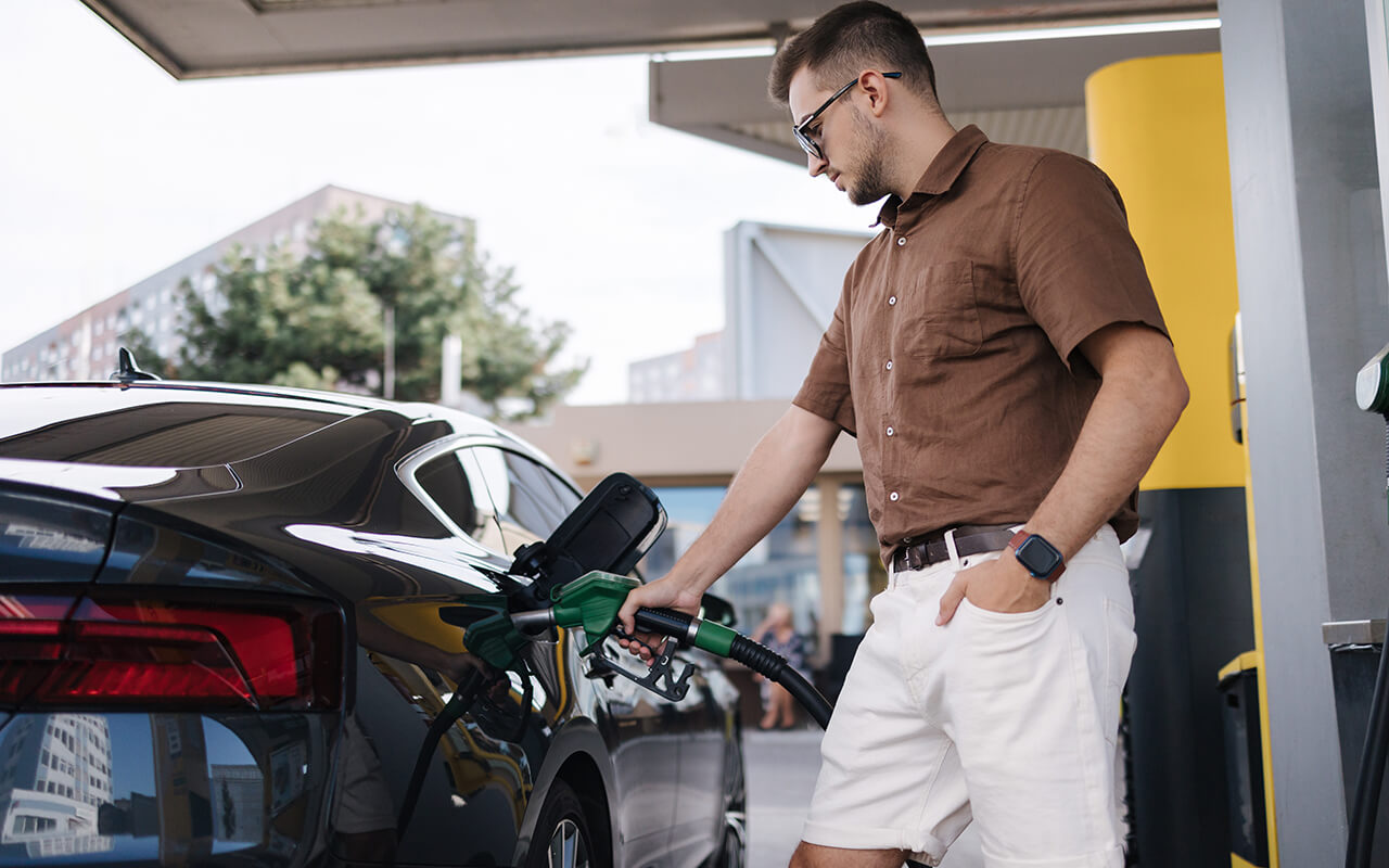 Man pumping gas at a station before a road trip
