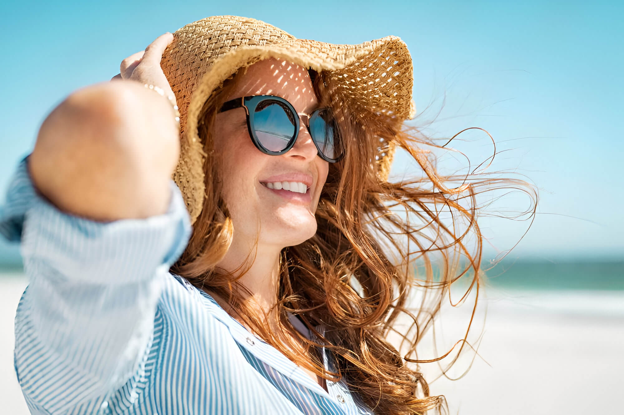 girl wearing a hat and sunglasses at the beach