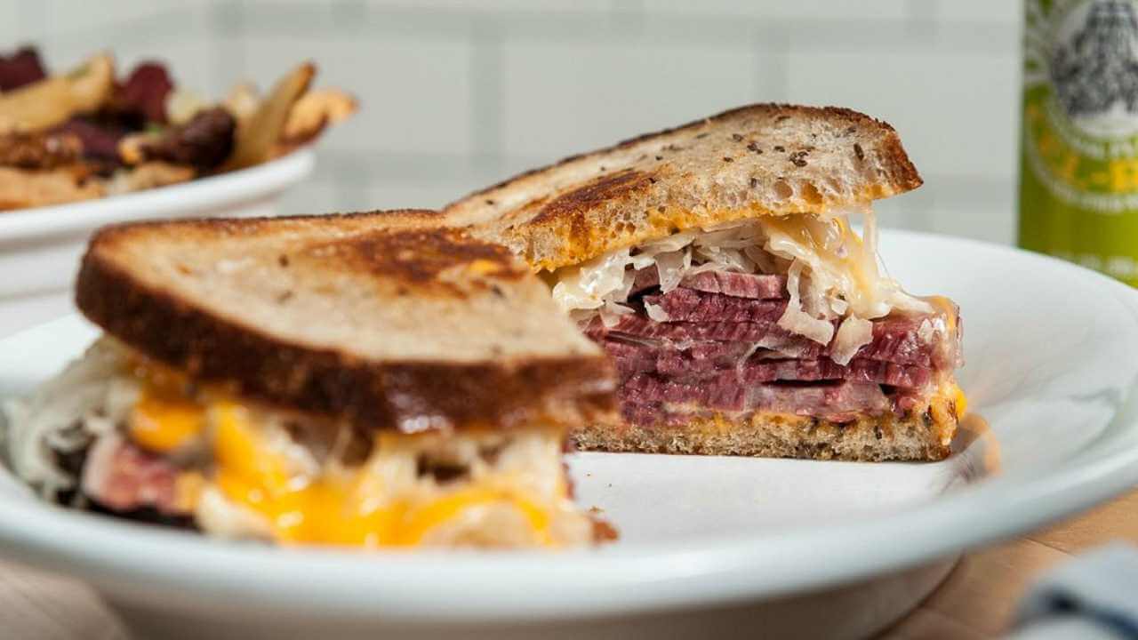 a corned beef sandwich is cut in half on a plate