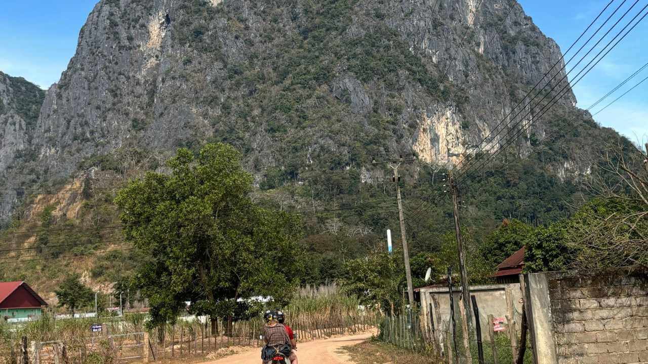 a motorcyclist rides down a dirt road in front of a mountain