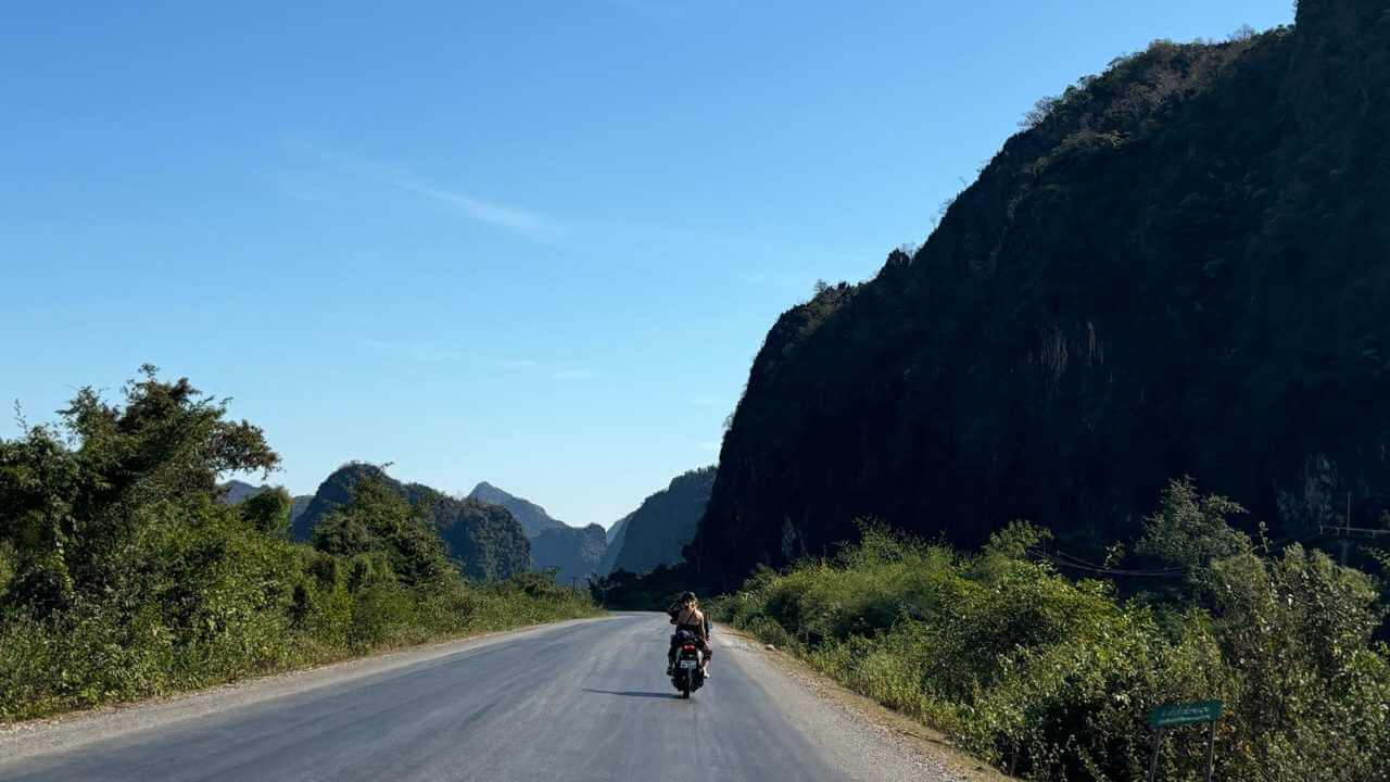 a person riding a motorcycle down a country road