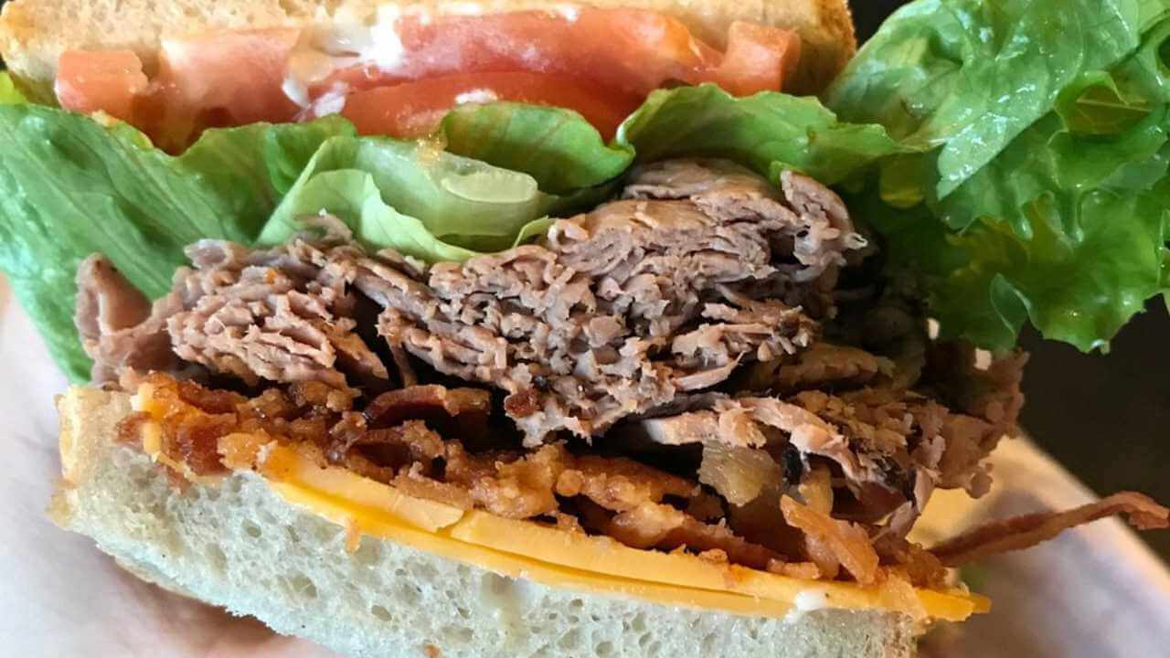a close up of a pulled pork sandwich with lettuce and tomato