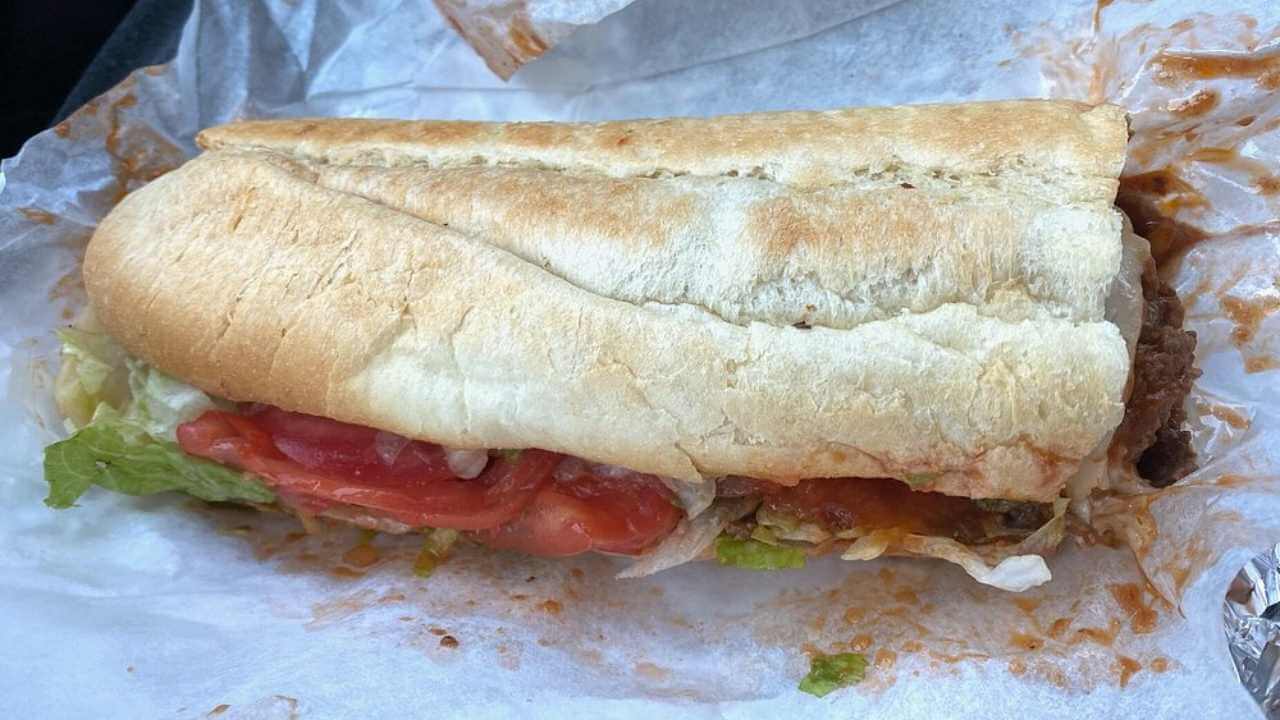 a close up of a sub sandwich with tomatoes and lettuce