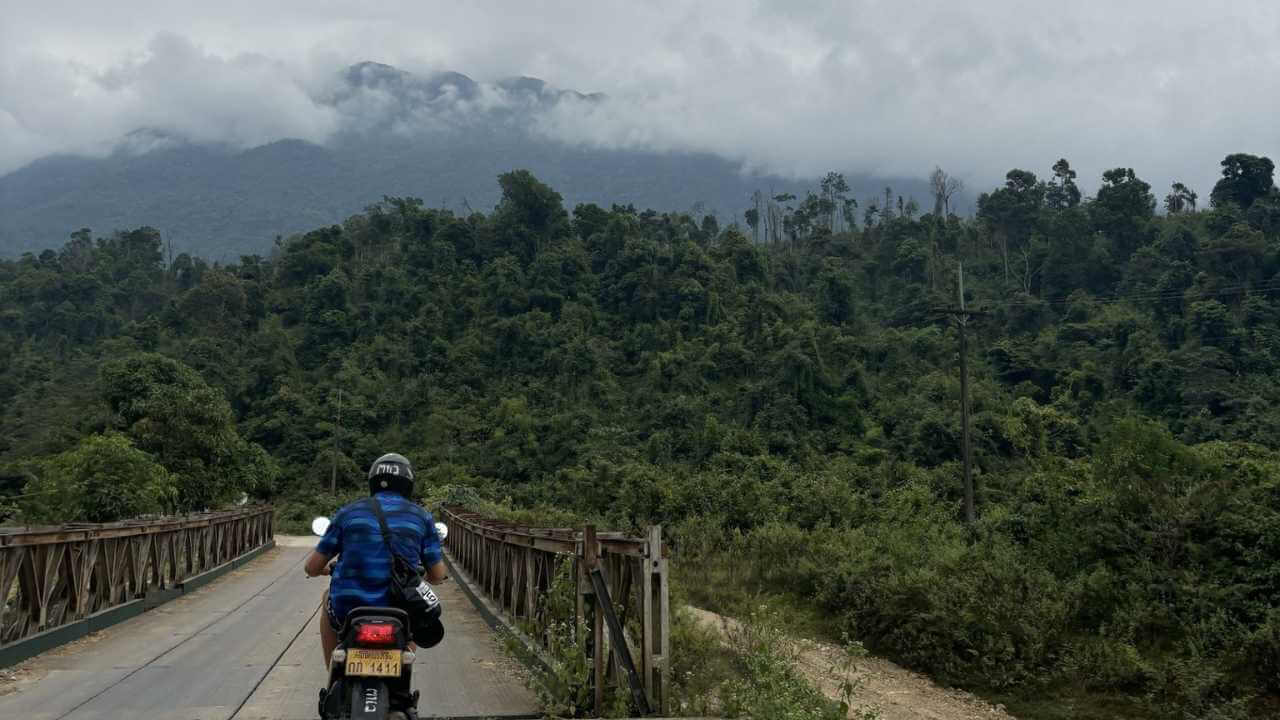 a person riding a motorcycle on a bridge over a river