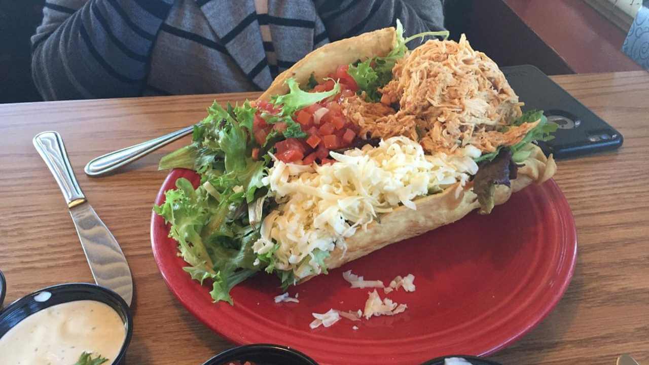 a person sitting at a table with a taco on a red plate