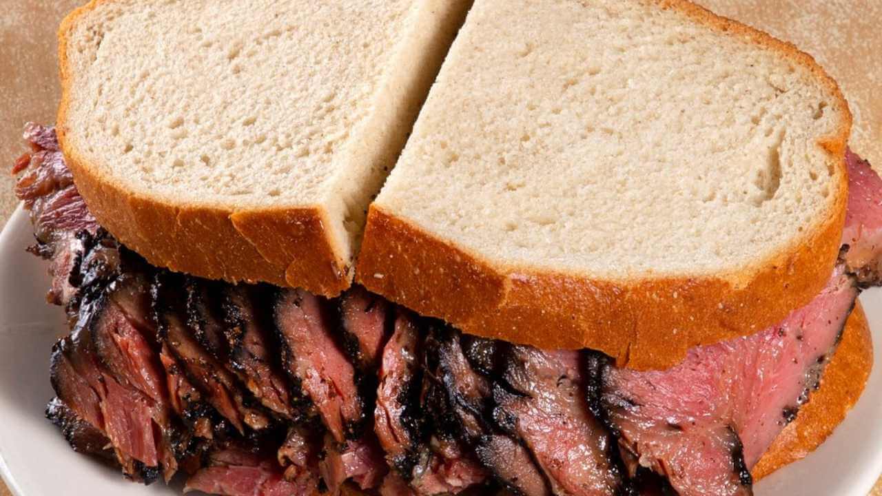 a roast beef sandwich on a plate with two slices of bread