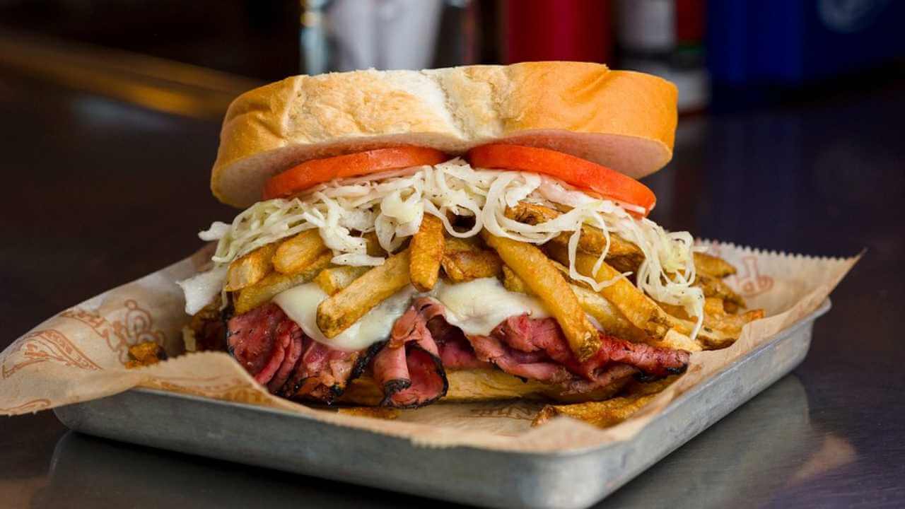 a large sandwich with french fries and meat on it