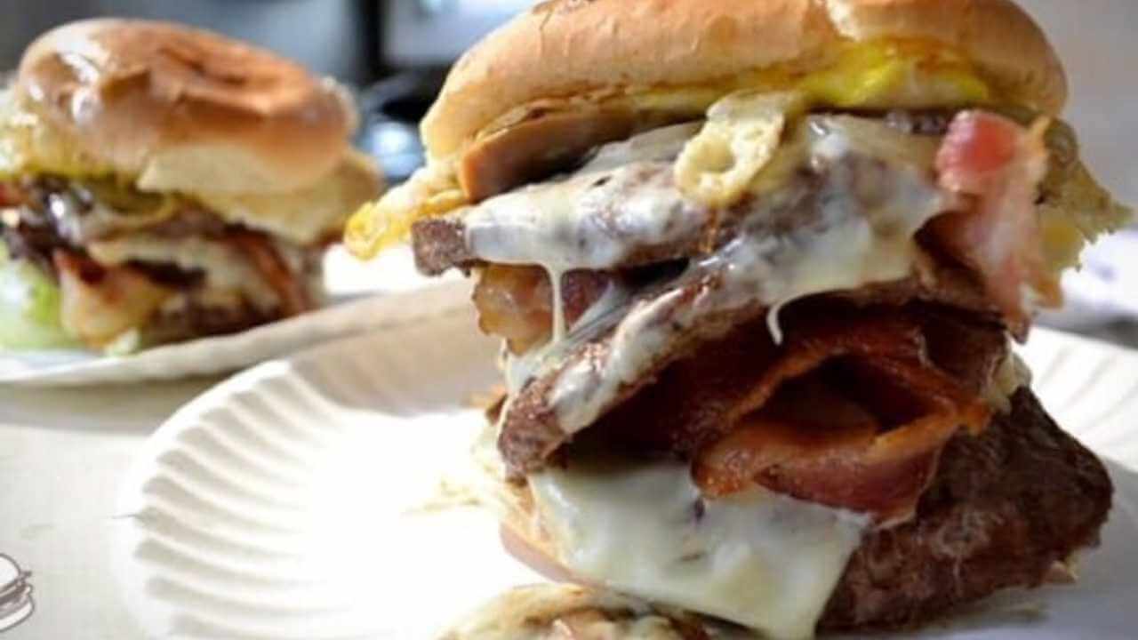 two hamburgers with bacon and cheese on them