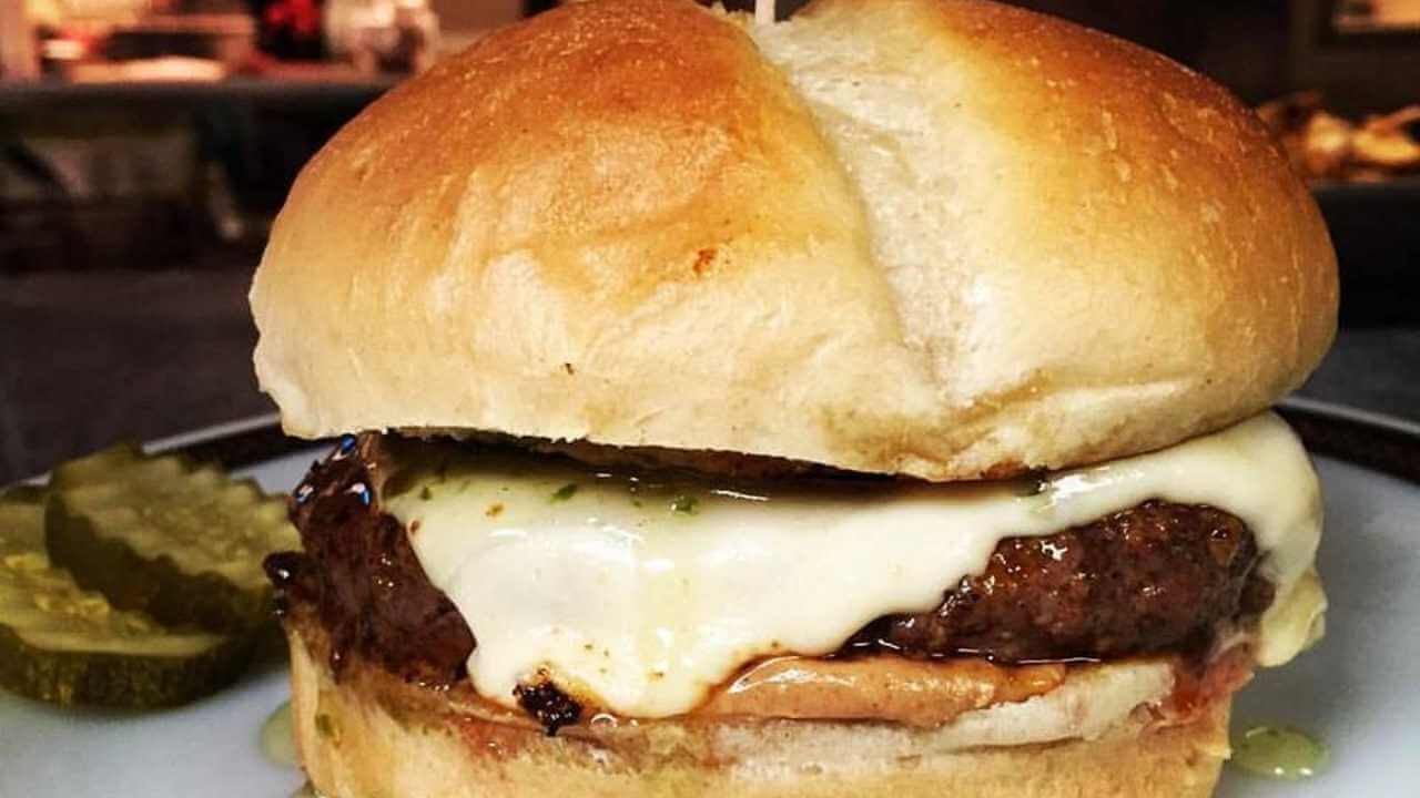 a hamburger with cheese and pickles sitting on top of a plate