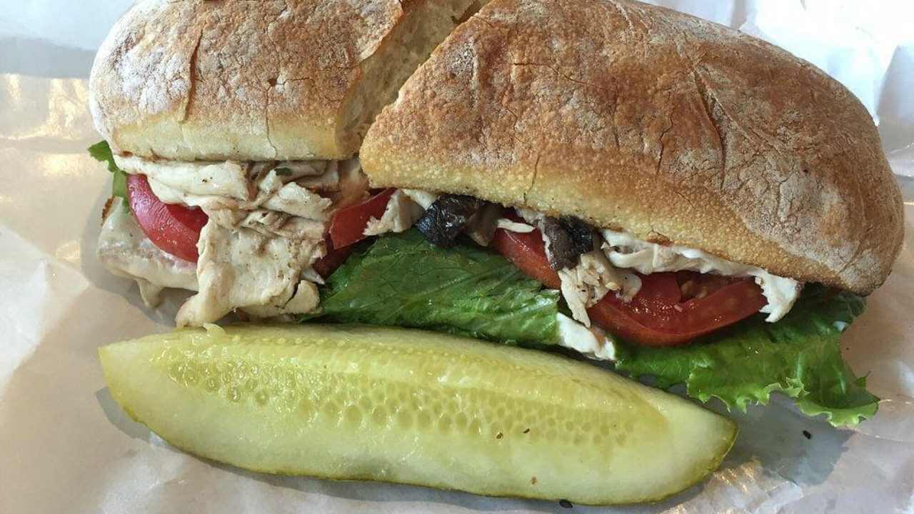 a sandwich and a pickle on a piece of white paper