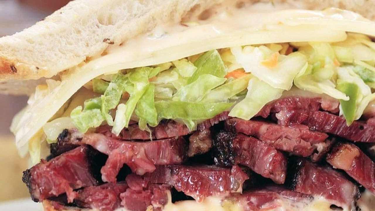 a corned beef sandwich with coleslaw on a white plate