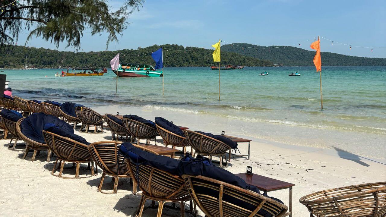 Several chairs are lined up on the beach next to the water