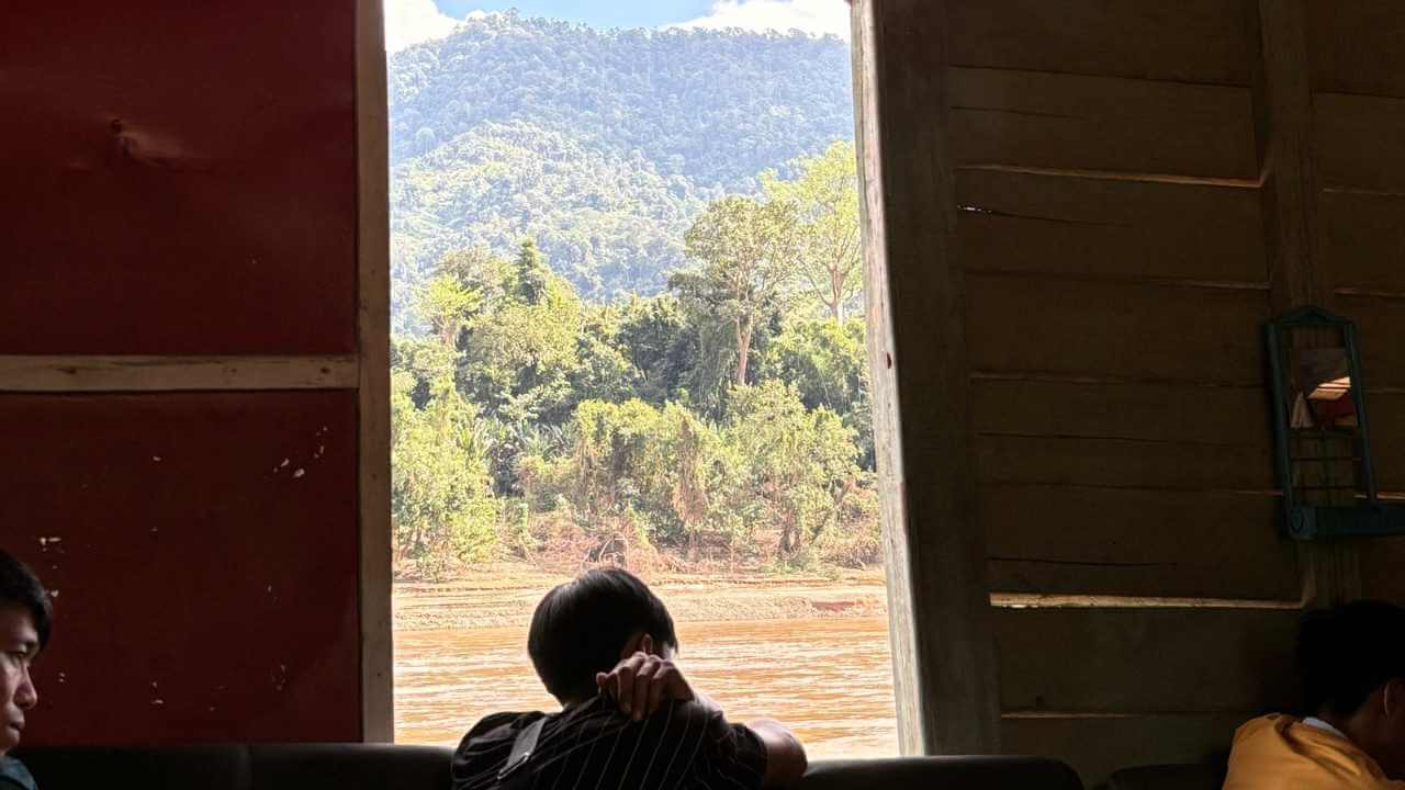 a group of people sitting at a table in front of a window with mountains in the background