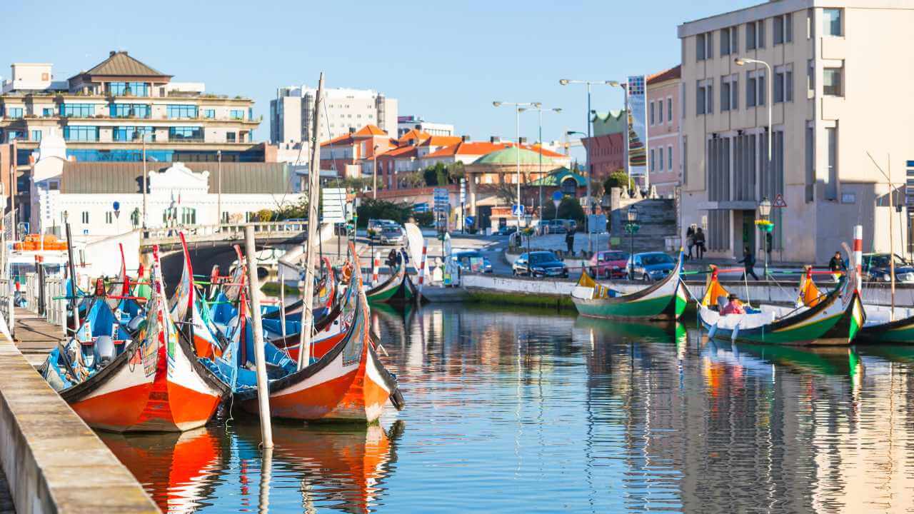 several boats are docked in a canal next to buildings