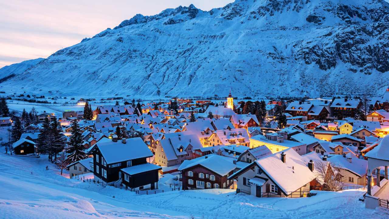 a snowy village in the mountains at dusk