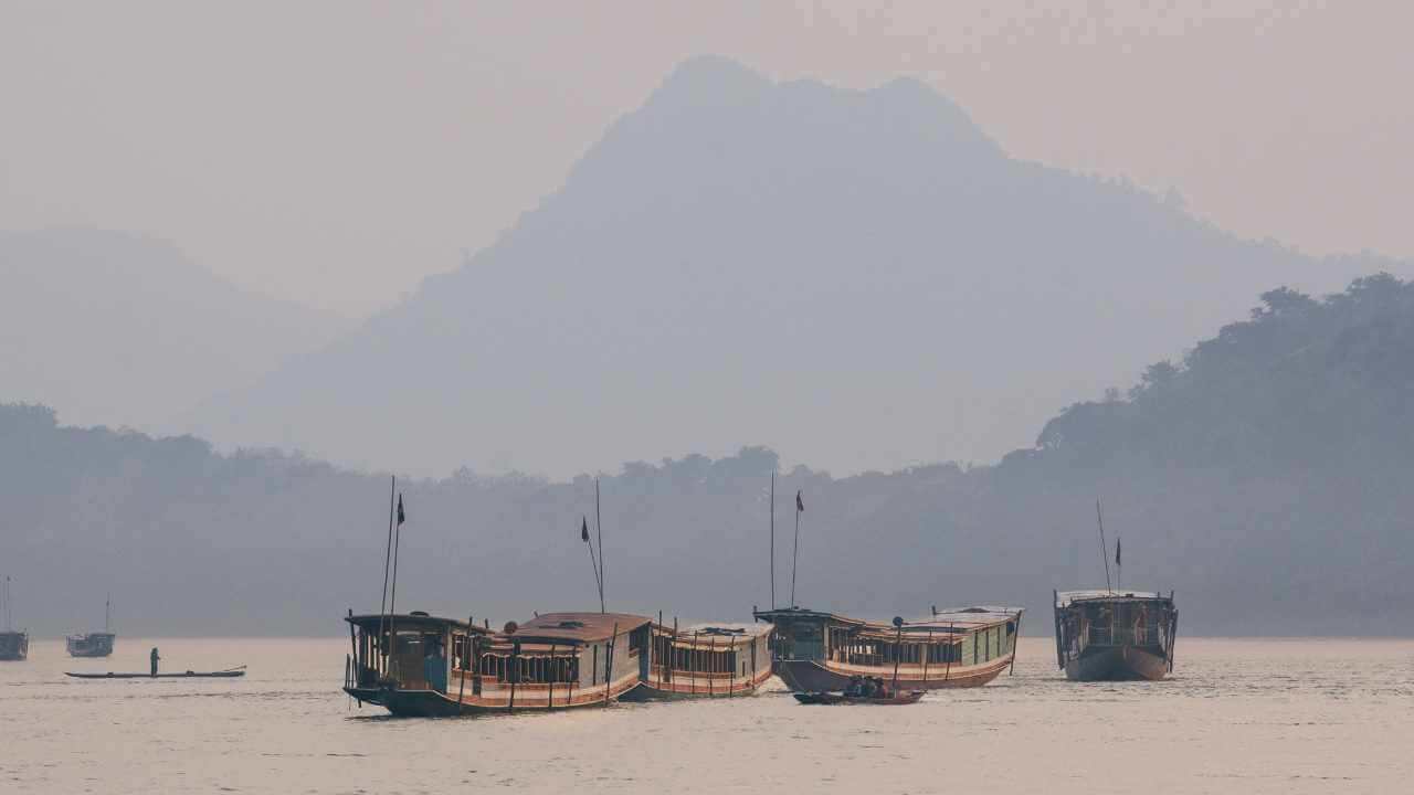 Several boats in the water with mountains in the background