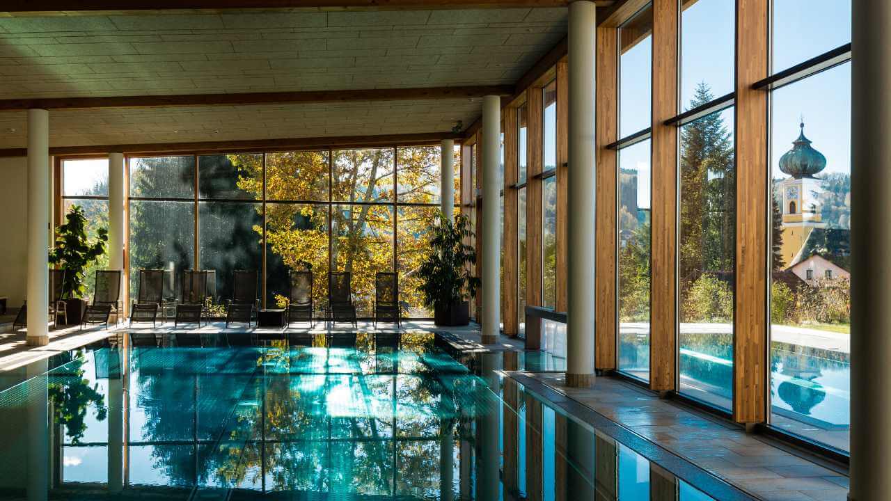 an indoor swimming pool surrounded by glass walls