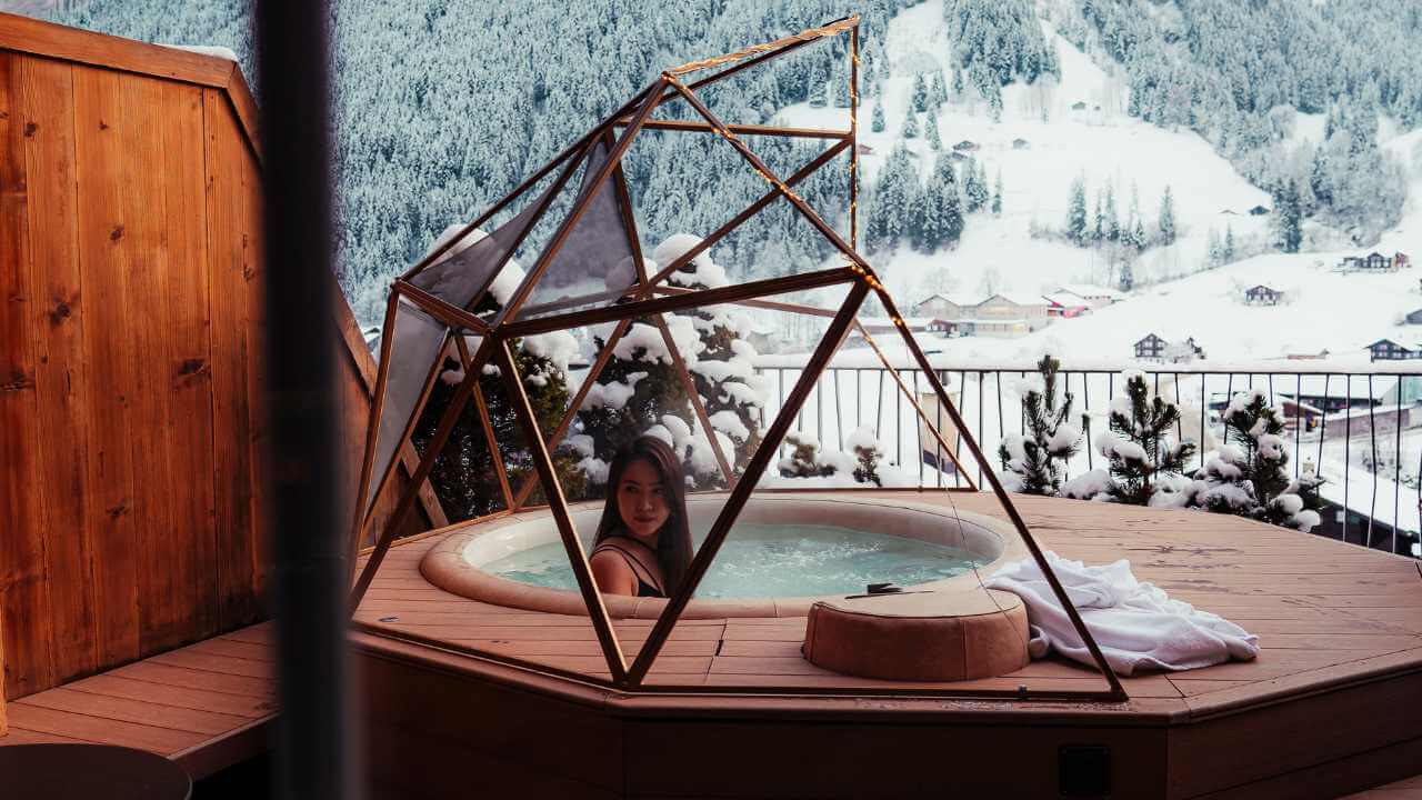 a person is sitting in a hot tub in front of a mountain