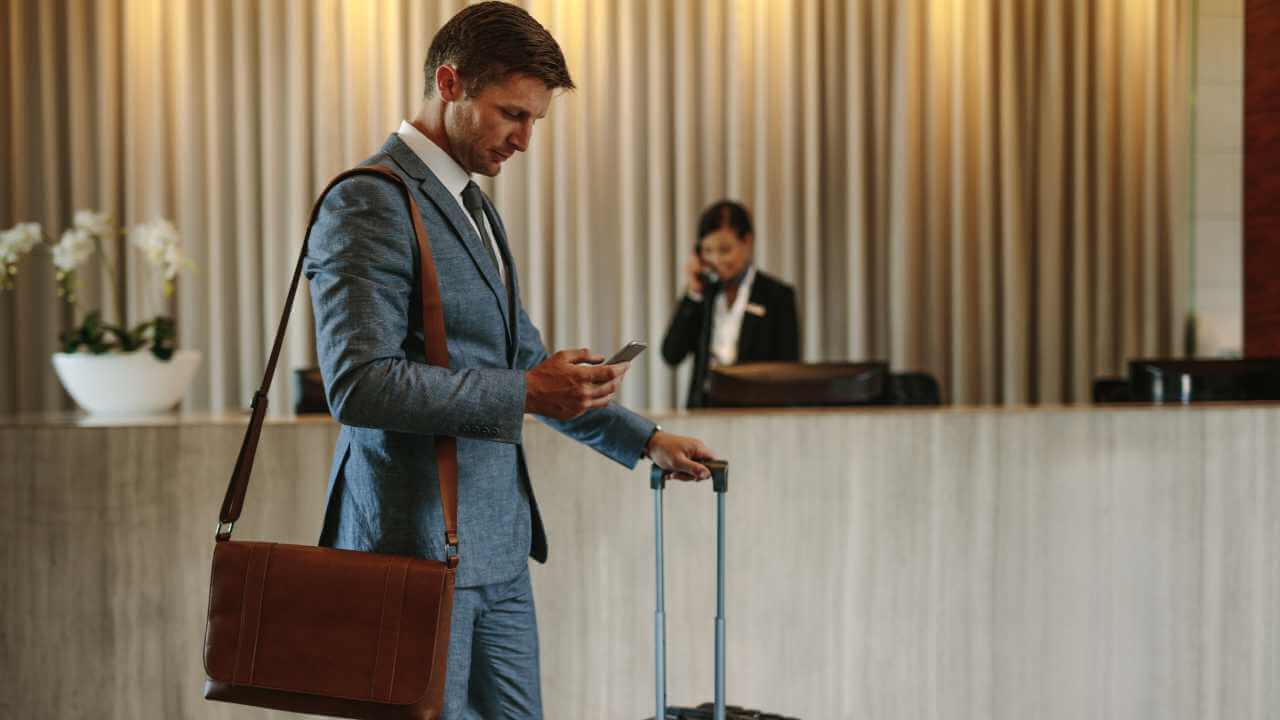 a person in a suit standing in front of a hotel looking at their phone