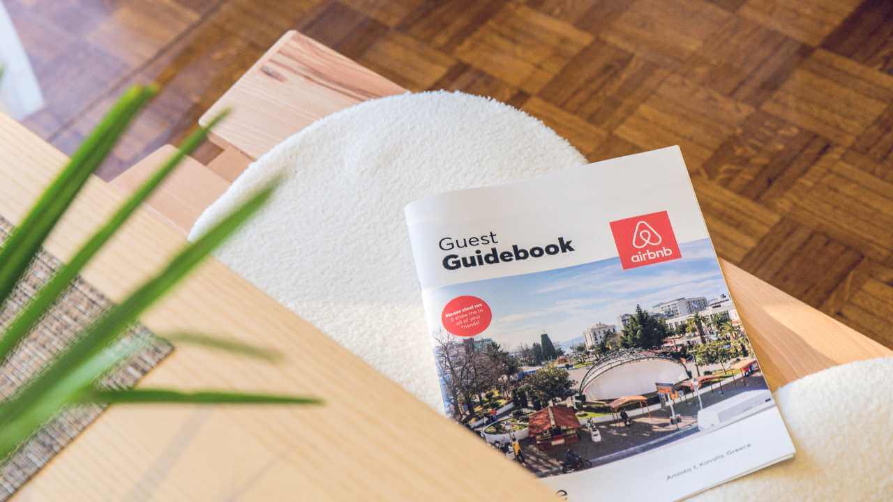 an airbnb guidebook on a table in front of a plant