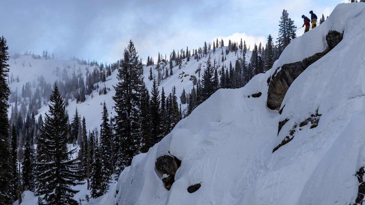 a group of skiers are climbing up the side of a snow covered mountain