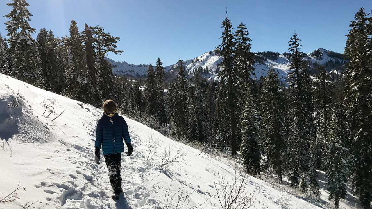 a person walking up a snow covered hill in the mountains