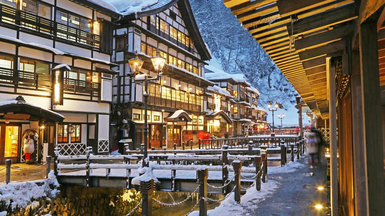 a snowy street lined with wooden buildings in japan