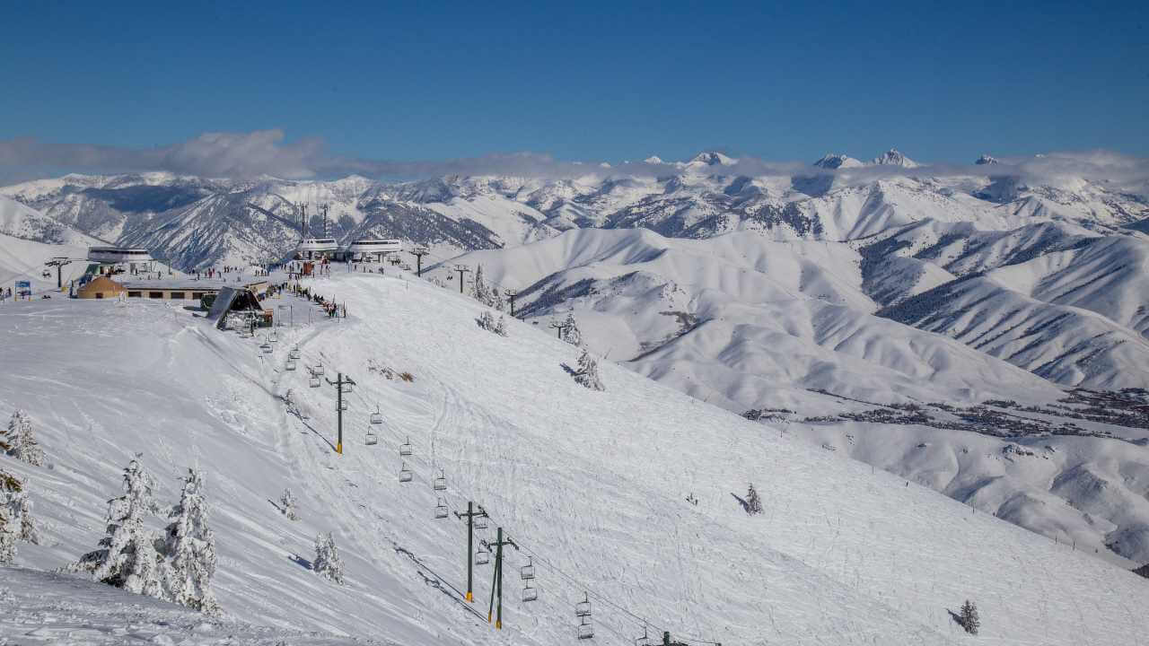 a ski lift is on top of a snow covered mountain