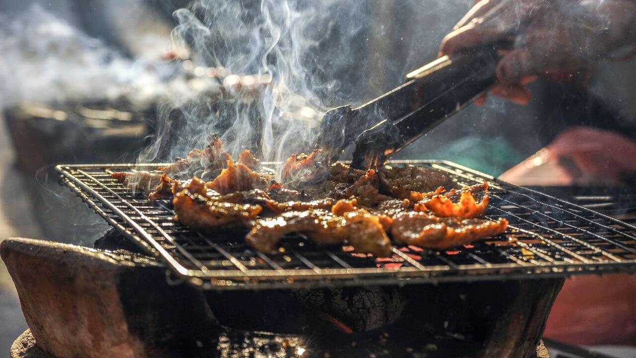 a person grilling food on a grill with smoke coming out of it