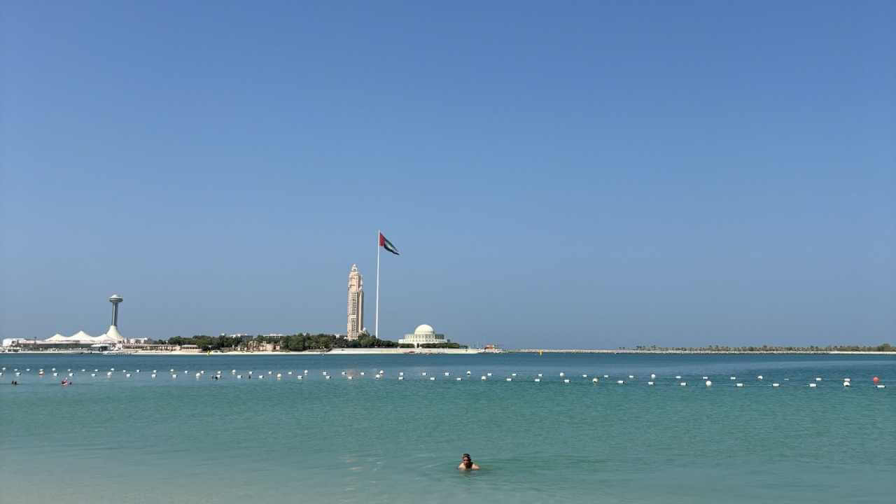 people swimming in a body of water near a large building