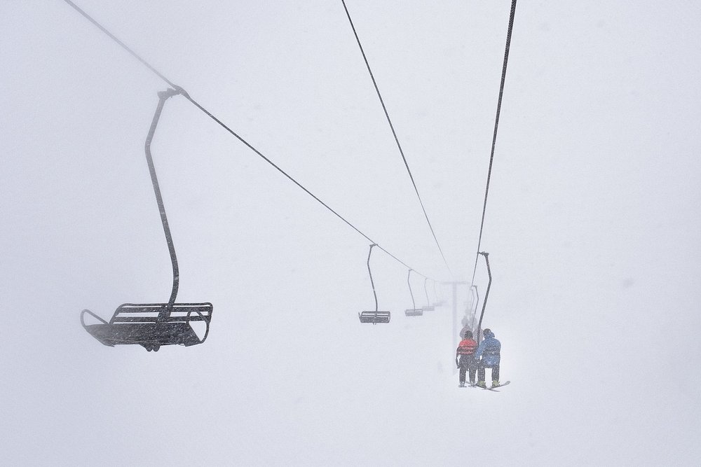 Chairlift carrying skiers in a whiteout at a North American ski resort