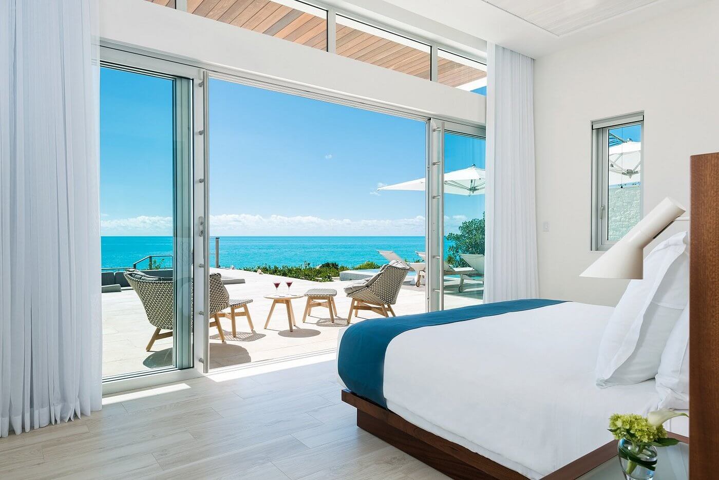 Oceanfront resort bedroom with open terrace overlooking turquoise water in Turks and Caicos.