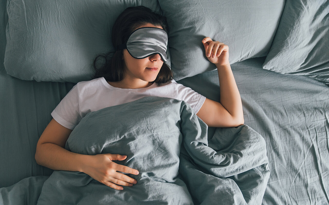Person wearing a sleep mask in bed