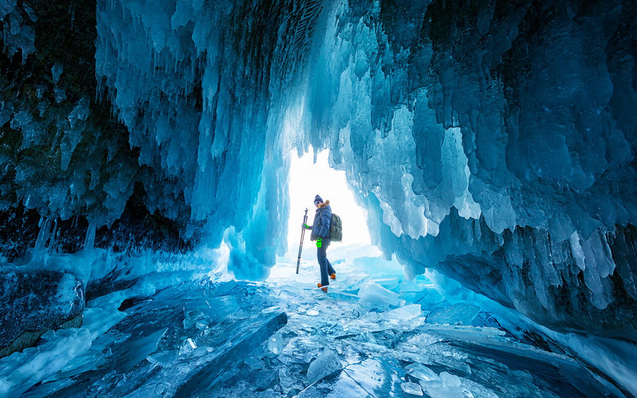 A tourist or photographer travels in the stunning ice cave on Lake Baikal, Russia.