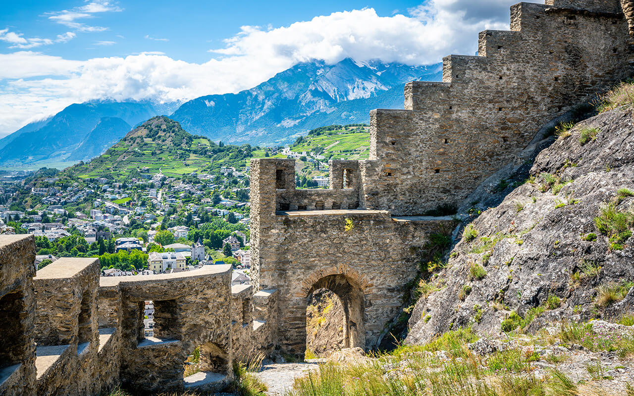 Entrance door and wall of the ruins of Tourbillon castle and Sion hill and city panorama in background Sion Valais Switzerland