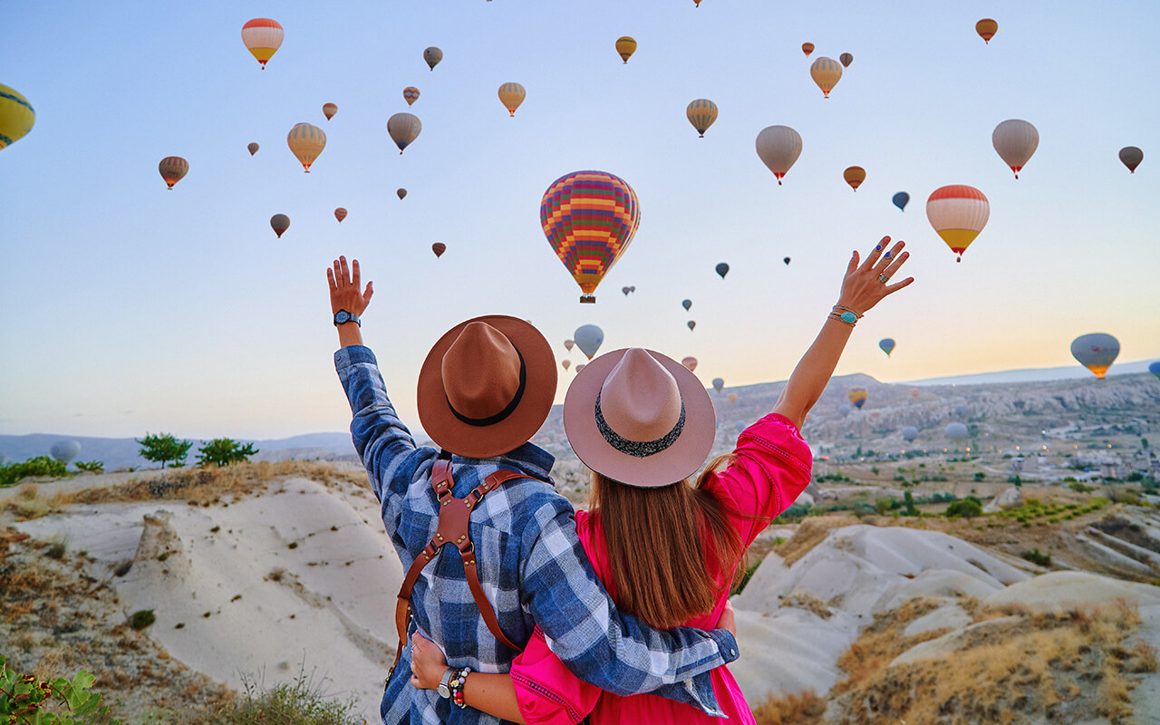 Traveling couple with open arms standing together in scenic valley in Anatolia, Kapadokya. 