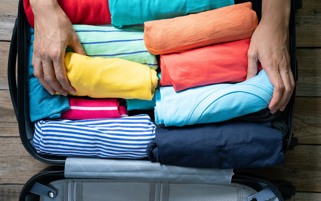 Person packing a suitcase with clothes