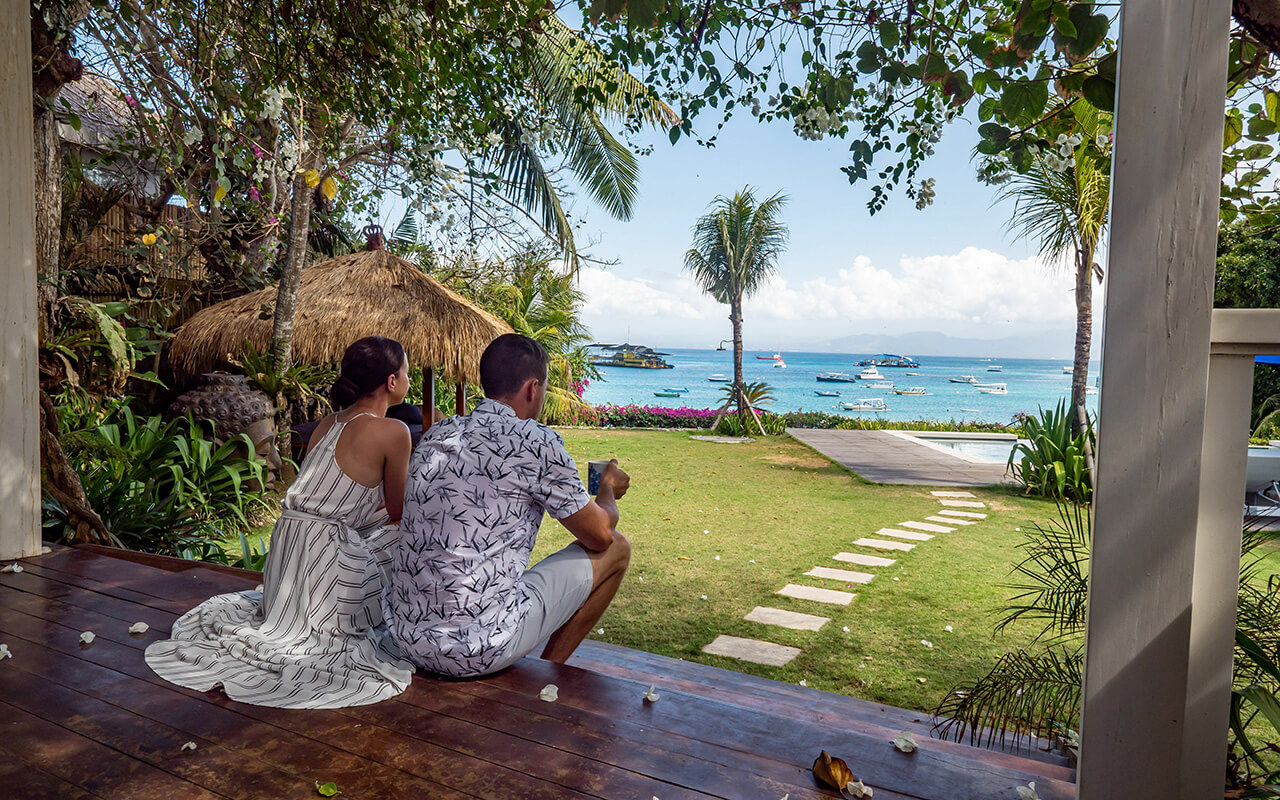 Couple enjoying a tropical beach view from a wooden deck.