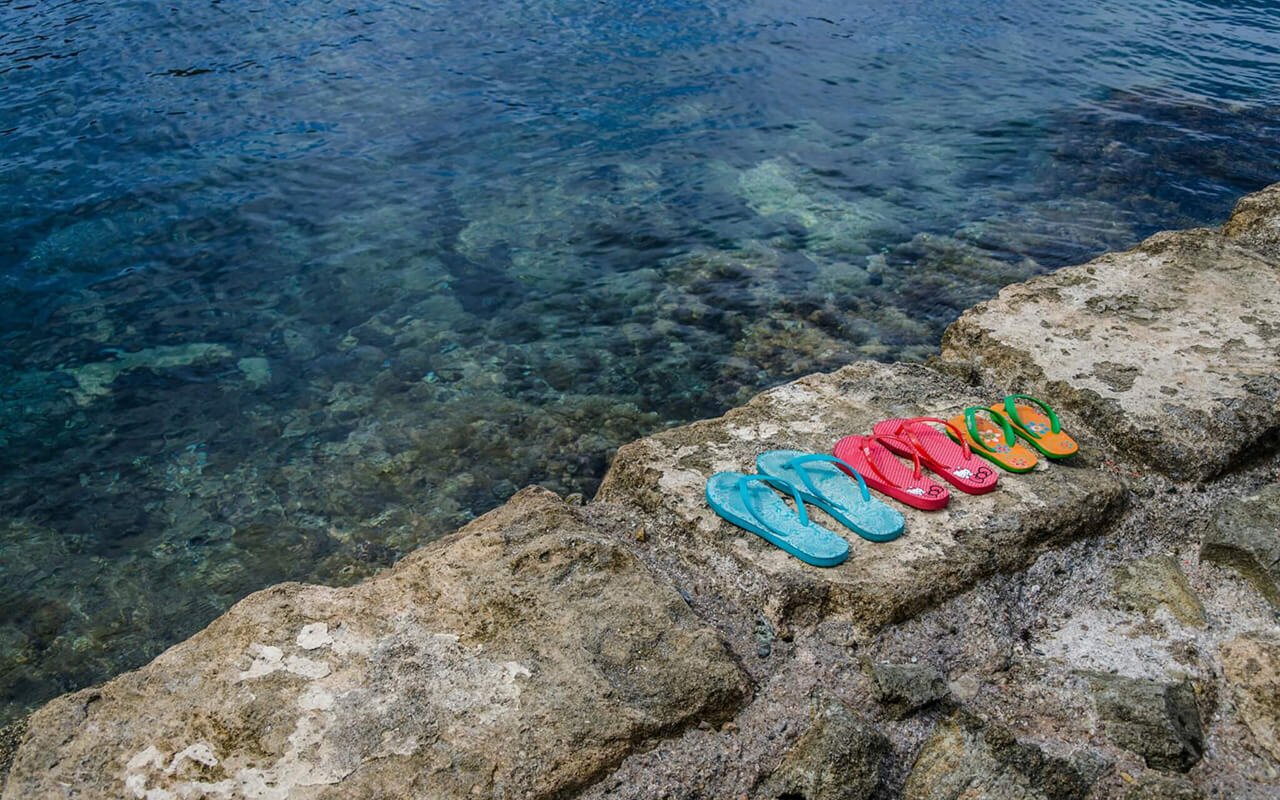 Three colorful flip flops by the sea.