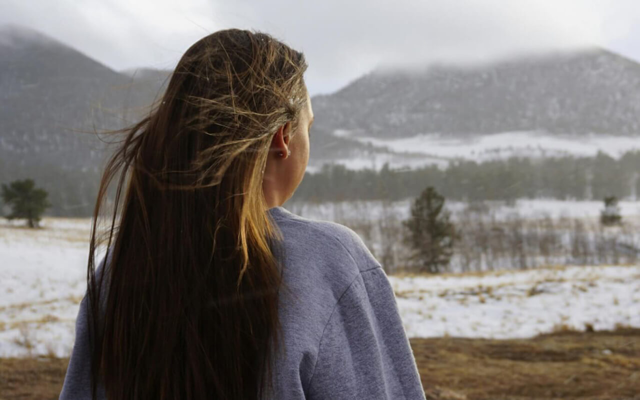 Girl with long hair looking at mountains
