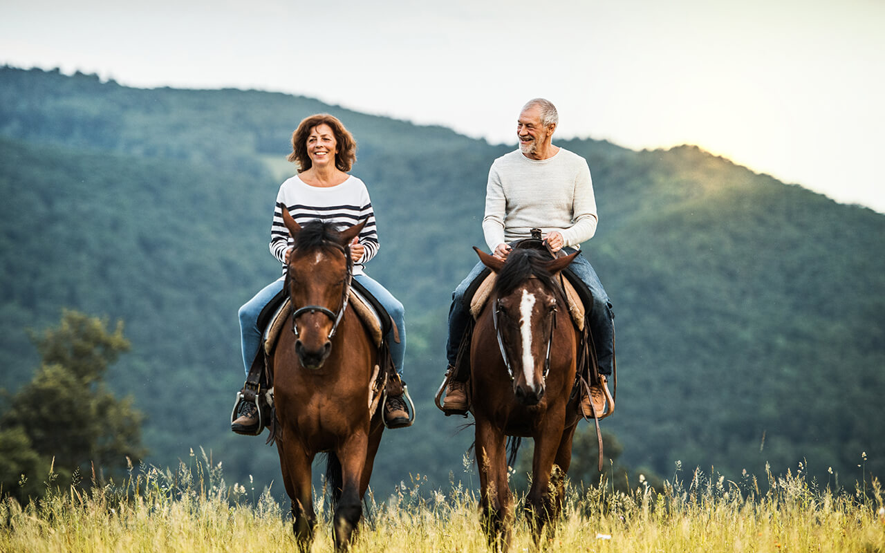 Couple horseback riding in a scenic mountain destination for horse lovers