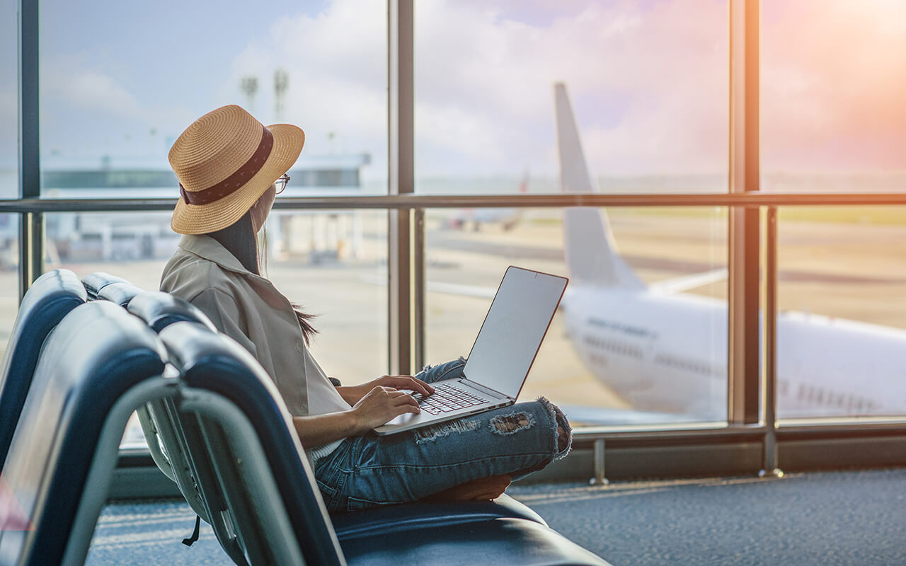 Woman typing on a laptop at an airport 
